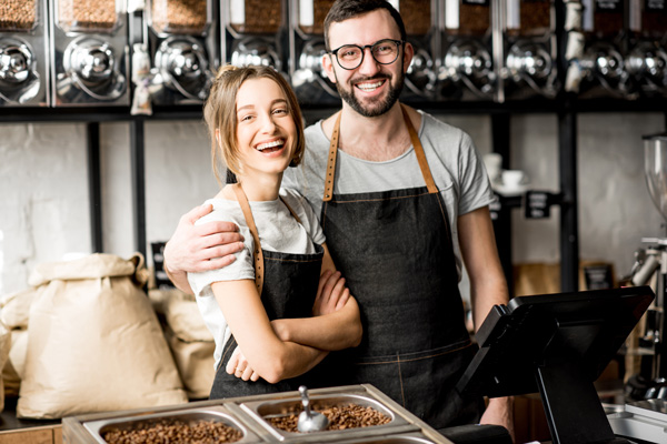 smiling baristas in a coffee shop surrounded by bags of coffee beans showcasing their passion for coffee and community 8 blends 8 varieties 8 flavors 8 beans